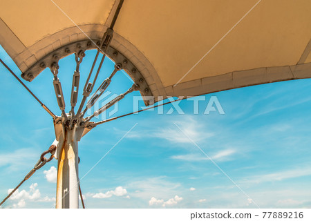 Connection points of tension membrane roof. Turnbuckle wire rope tension for tension membrane roof on a blue sky background. 77889216