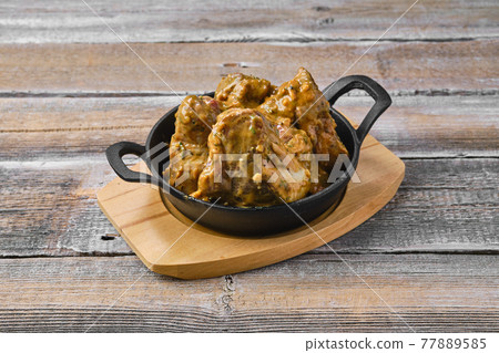 Lamb saddle marinated in mustard in cast iron skillet Lamb saddle marinated in mustard in cast iron skillet 77889585
