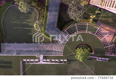 Top down aerial view of outdoor Green garden and Golf Driving Range surrounding palms in the condominium. 77889716