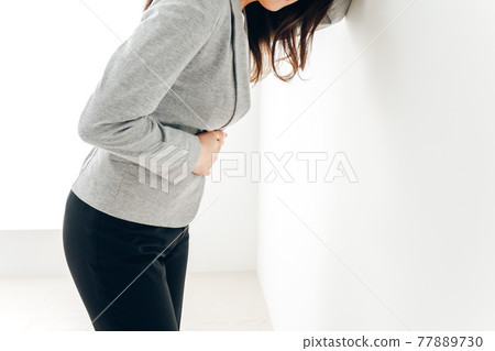Young woman suffering from abdominal pain and menstrual cramps 77889730