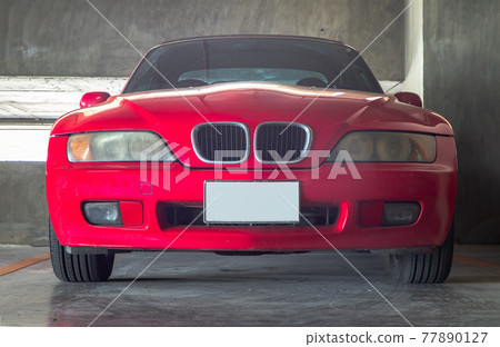 In front of red Sports car parked in the Parking lot. 77890127
