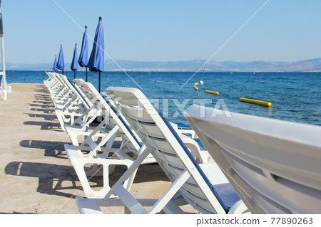 Rows of empty chaise-lounges 77890263