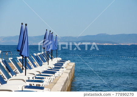 Rows of empty chaise-lounges 77890270