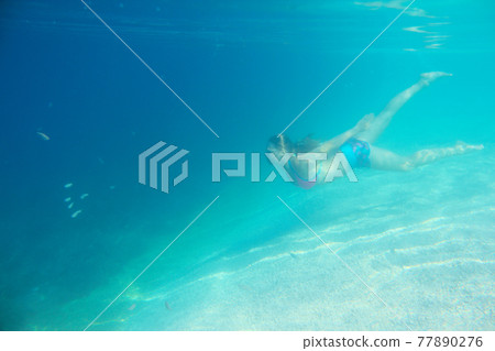 Woman swimming underwater Woman swimming underwater 77890276