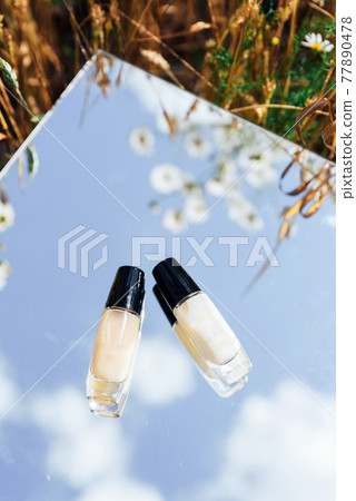 White tubes of cream in a field on a mirror surface White tubes of cream in a field on a mirror surface 77890478