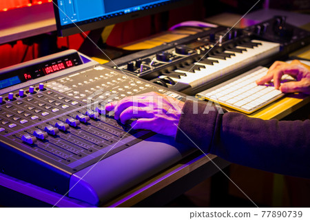 close up male sound engineer hand mixing music on digital audio mixing board in sound studio. music production concept 77890739