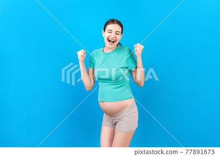 Young beautiful pregnant woman on isolated colored background celebrating surprised and amazed for success with arms raised and open eyes. Winner concept 77891673