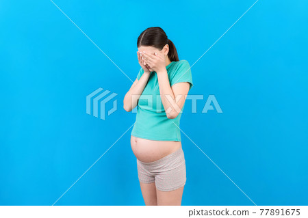Beautiful young pregnant woman feeling head ache on colored background isolated. Stressed pregnant woman or mother problems 77891675