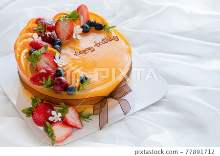 Orange cake with happy birth day and topped with orange, strawberry, blueberry Orange cake with happy birth day and topped with orange, strawberry, blueberry 77891712