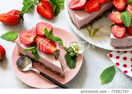 Summer diet dessert, cheesecake without baking. Strawberry cheesecake on a chocolate granola with fresh strawberries on a light gray table top. 77891747