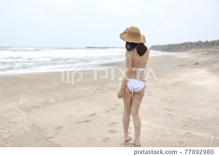 A young woman in a bikini posing on the coast of Kujukuri A young woman in a bikini posing on the coast of Kujukuri 77892980
