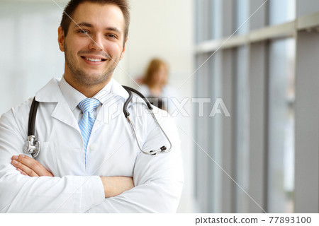 Male dark hair doctor standing in the modern clinic. Perfect medical service in the hospital. Medicine concept Male dark hair doctor standing in the modern clinic. Perfect medical service in the hospital. Medicine concept 77893100