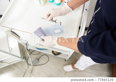 Top view of doctor beautician holding a syringe with beauty product for making face injection Top view of doctor beautician holding a syringe with beauty product for making face injection 77893129