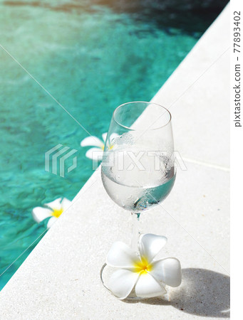 Glass of water refreshment drink on a pool side Glass of water refreshment drink on a pool side 77893402