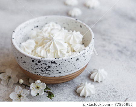 Small white meringues in the  ceramic bowl 77895995