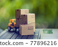 Logistic and cargo freight concept: Fork-lift a truck moves a paper box on table. depicts International freight or shipping service for online shopping. 77896216