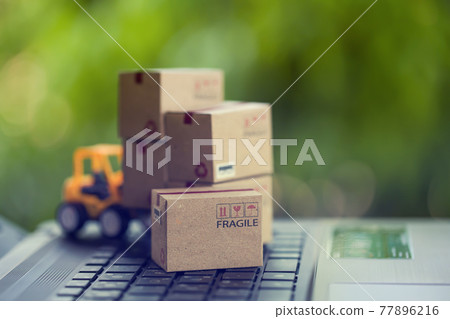 Logistic and cargo freight concept: Fork-lift a truck moves a paper box on table. depicts International freight or shipping service for online shopping. Logistic and cargo freight concept: Fork-lift a truck moves a paper box on table. depicts International freight or shipping service for online shopping. 77896216