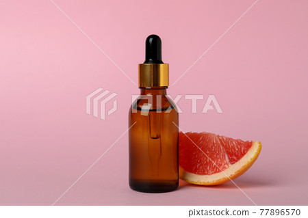 Dropper bottle with oil and grapefruit slice on pink background Dropper bottle with oil and grapefruit slice on pink background 77896570