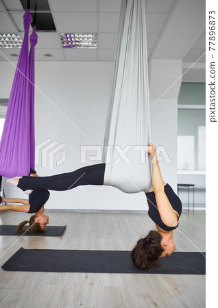 Aerial anti-gravity yoga, hanging on hammocks 77896873