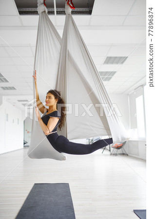 Aerial yoga, slim woman poses on hammock 77896874