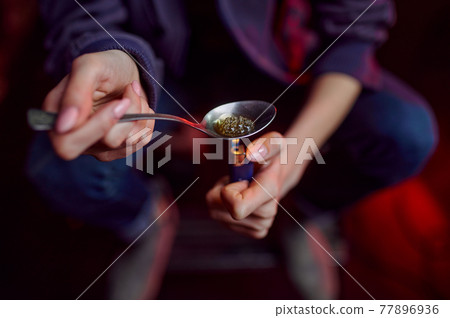 Drug addict with spoon and fire prepares dose 77896936