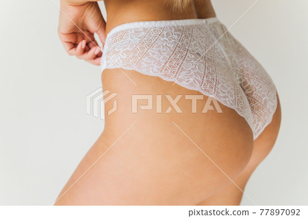 Cropped photo of an attractive young woman s hips wearing in black lingerie with stockings, laces. Sideways. Erotic ladies fashion concept. 77897092