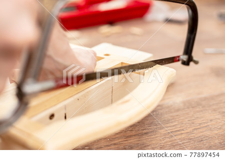 Sawing a wooden product with a hand saw. Carpentry works. Hobby.  77897454