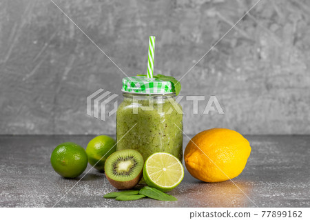 Freshly made kiwi lime and spinach smoothie on a gray concrete background. Freshly made kiwi lime and spinach smoothie on a gray concrete background. 77899162