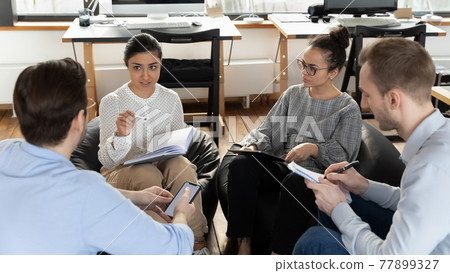 Diverse colleagues employees brainstorming, involved in briefing, sitting in circle Diverse colleagues employees brainstorming, involved in briefing, sitting in circle 77899327