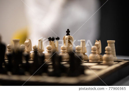 Chess pieces on board in initial position on blurred background Chess pieces on board in initial position on blurred background 77900365