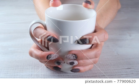 Beautiful manicured nails in the form of chocolate candies on female hands close-up and a cup of Beautiful manicured nails in the form of chocolate candies on female hands close-up and a cup of 77900620