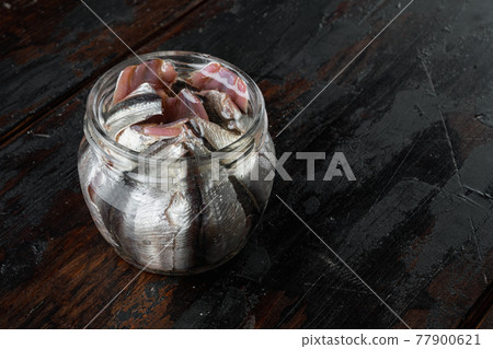 Salted anchovy fillets, in glass jar, on old dark wooden table background., with copyspace and space for text Salted anchovy fillets, in glass jar, on old dark wooden table background., with copyspace and space for text 77900621