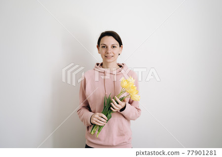 Millennial caucasian woman with bouquet of yellow tulips on white background. Lifestyle portrait of Millennial caucasian woman with bouquet of yellow tulips on white background. Lifestyle portrait of 77901281