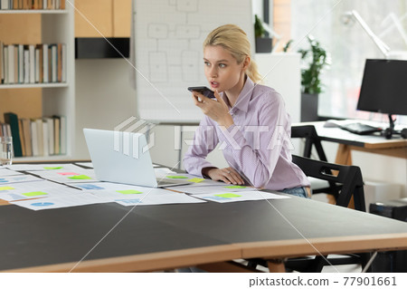 Confident businesswoman recording audio voice message on smartphone in office 77901661