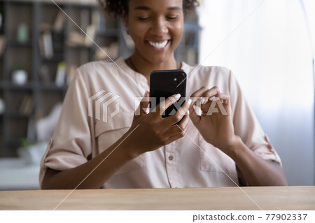 Smiling young african woman using smartphone indoors. 77902337