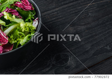 Fresh leaves of different lettuce salad, on black wooden table background with copy space for text 77902872