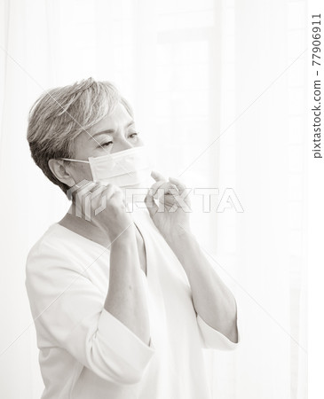 Senior asian woman wearing surgical mask during coronavirus and flu outbreak. Virus and illness protection, home quarantine. COVID-19. Taking on or taking off masks. 77906911