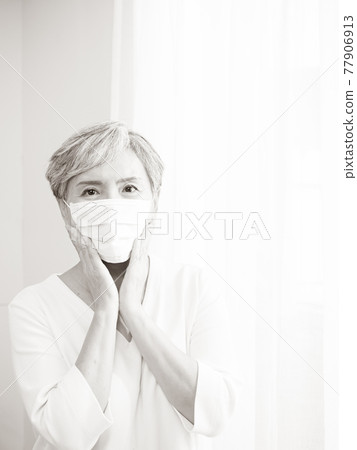 Senior asian woman wearing surgical mask during coronavirus and flu outbreak. Virus and illness protection, home quarantine. COVID-19. Taking on or taking off masks. Senior asian woman wearing surgical mask during coronavirus and flu outbreak. Virus and illness protection, home quarantine. COVID-19. Taking on or taking off masks. 77906913