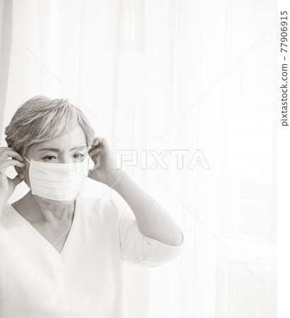 Senior asian woman wearing surgical mask during coronavirus and flu outbreak. Virus and illness protection, home quarantine. COVID-19. Taking on or taking off masks. Senior asian woman wearing surgical mask during coronavirus and flu outbreak. Virus and illness protection, home quarantine. COVID-19. Taking on or taking off masks. 77906915