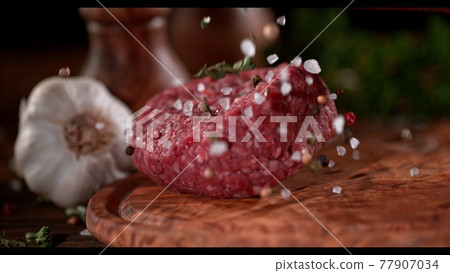 Super slowmotion footage of strewing salt and herbs at fresh raw beef meat burger, 1000fps 77907034