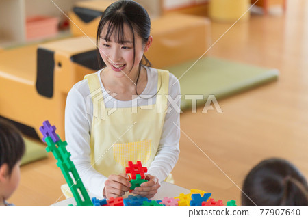 Children and nursery teachers playing with blocks 77907640