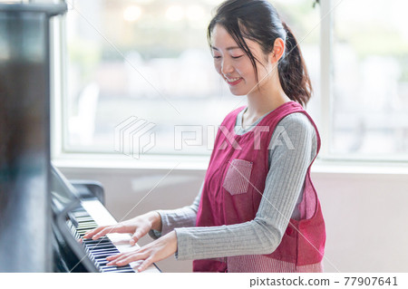 Nursery teacher playing the piano 77907641
