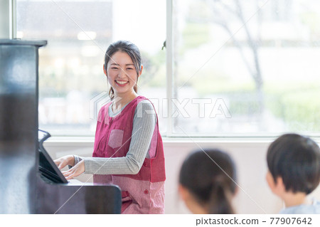 A nursery teacher playing the piano and a kindergarten singing 77907642