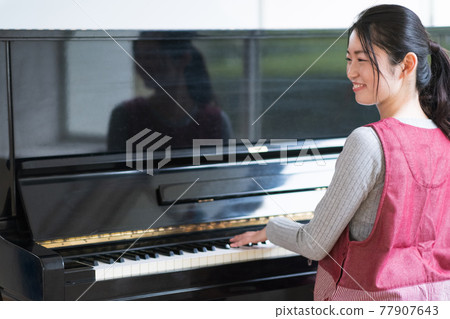 Nursery teacher playing the piano 77907643