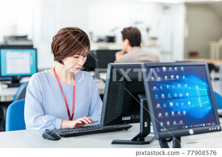 A young business woman using a computer in a bright office A young business woman using a computer in a bright office 77908576