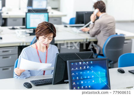 A young business woman using a computer in a bright office 77908631