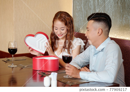 Woman opening romantic present Woman opening romantic present 77909217