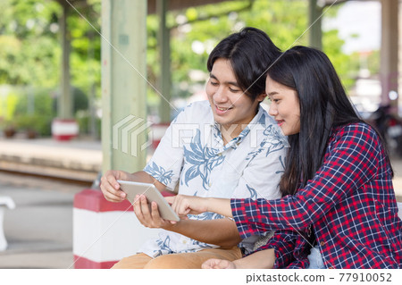 Young asian couple backpacker using tablet for find destination trip at railway station 77910052
