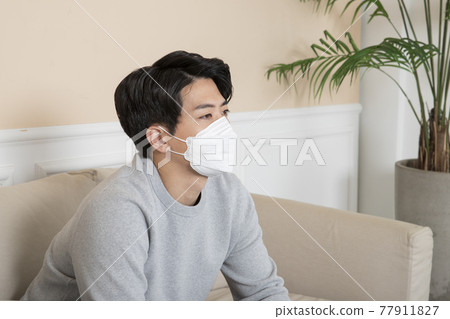 Asian man with mask on sofa 77911827