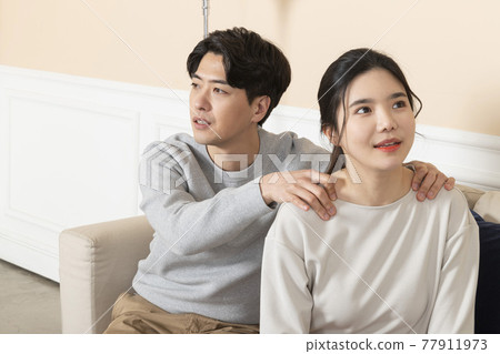 Asian wife massaging shoulders of husband 77911973